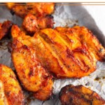 Grilled honey chipotle chicken thighs on a baking sheet lined with parchment paper.