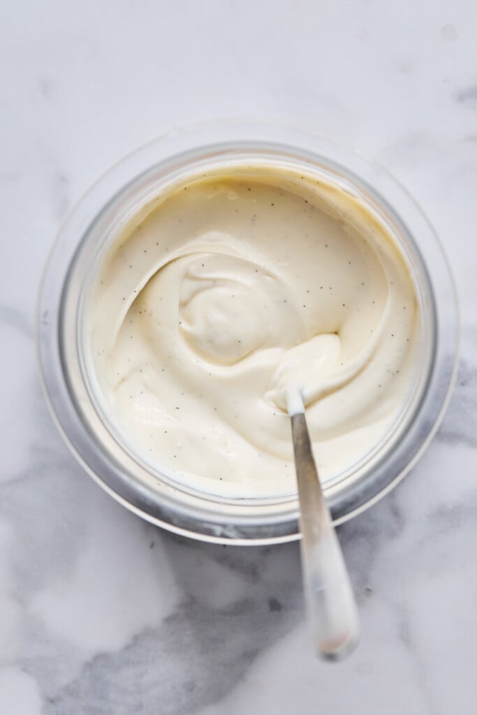 Greek yogurt mixed with honey and vanilla in a pint container. There is a spoon in the container as well.