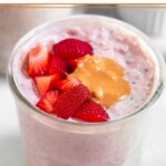 A jar of strawberries and cream overnight oats topped with diced strawberries and peanut butter.
