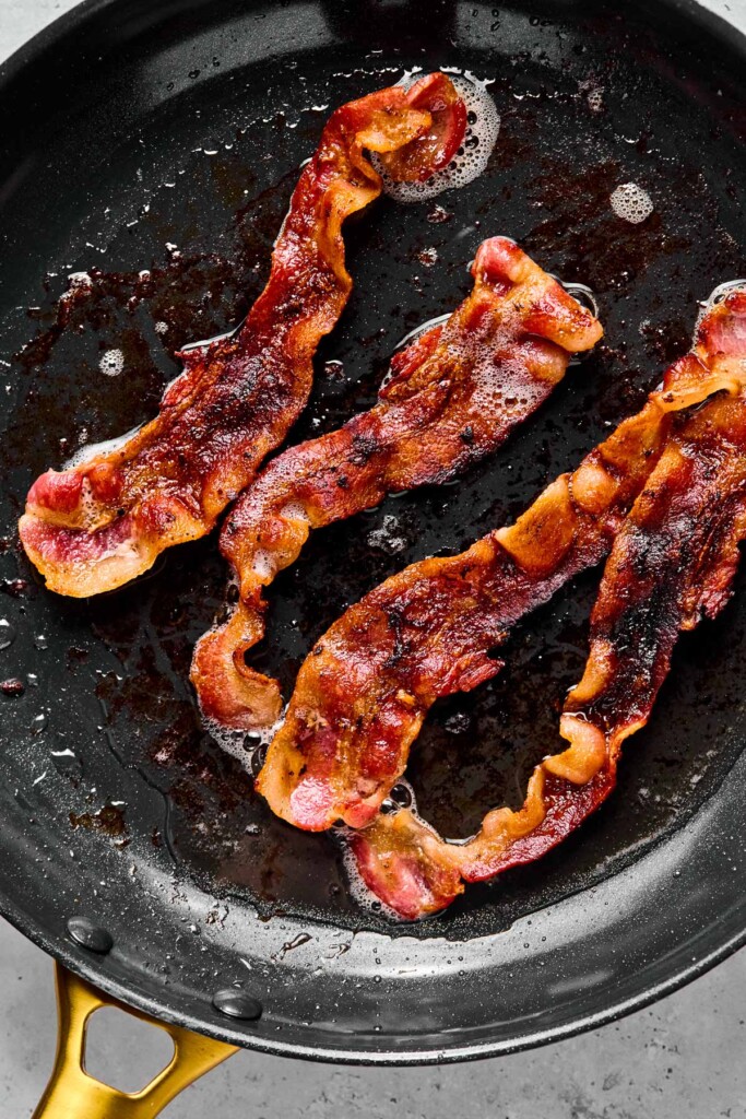 Skillet with 4 pieces of cooked bacon in it.