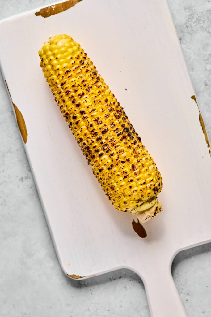 Cutting corn with an ear of corn that has been charred on it.