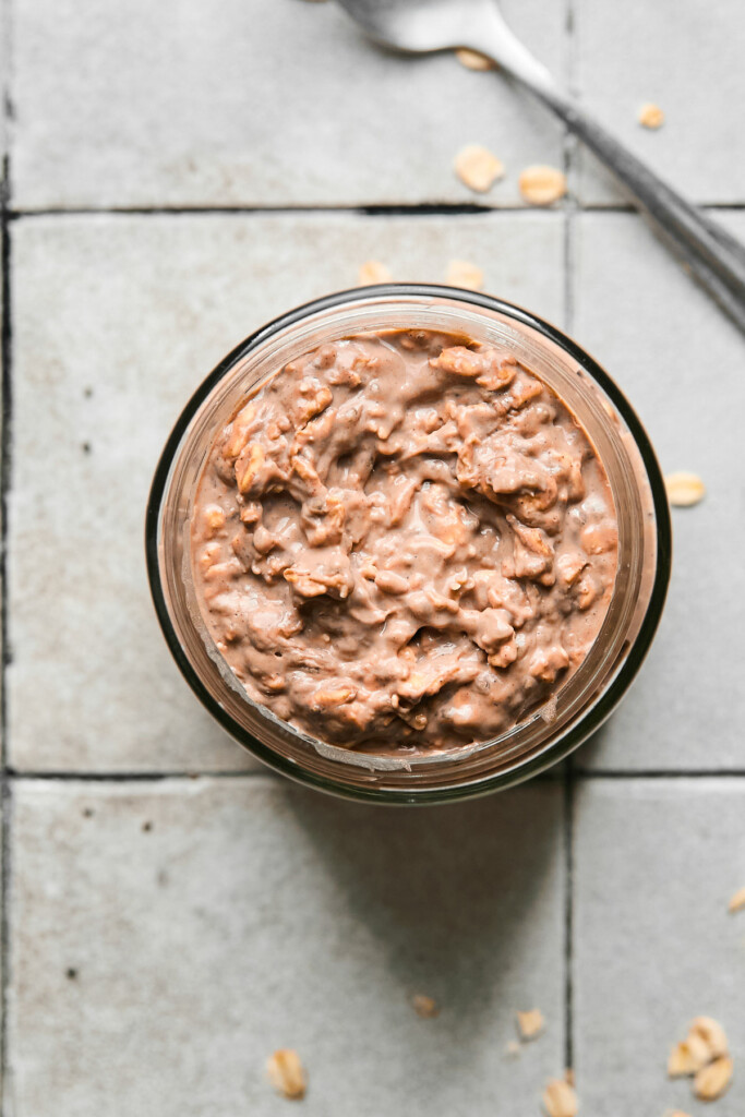 Overhead shot of chocolate overnight oats in a jar with in a spoon next to it.