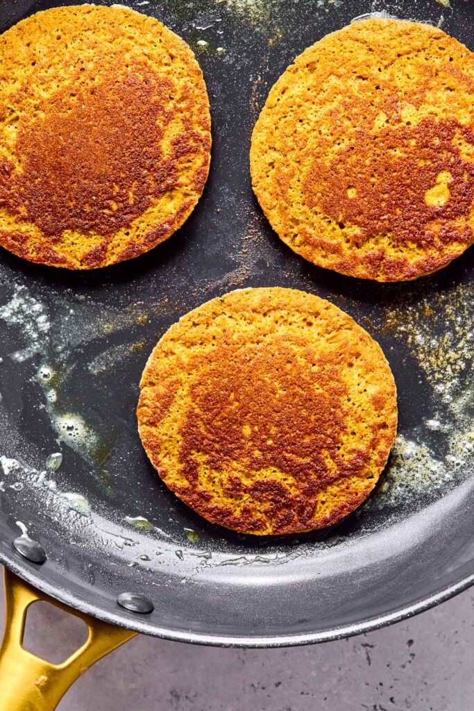 Skillet with three protein pumpkin pancakes in it.