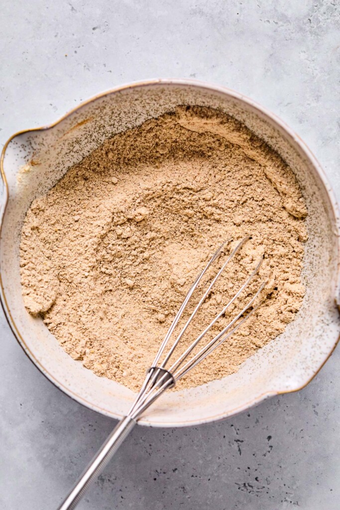 An overhead shot of a bowl with flour and spices mixed together. A whisk is also in it.