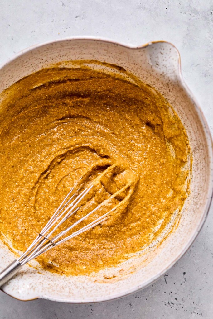 A bowl with a wet batter with a whisk in it.