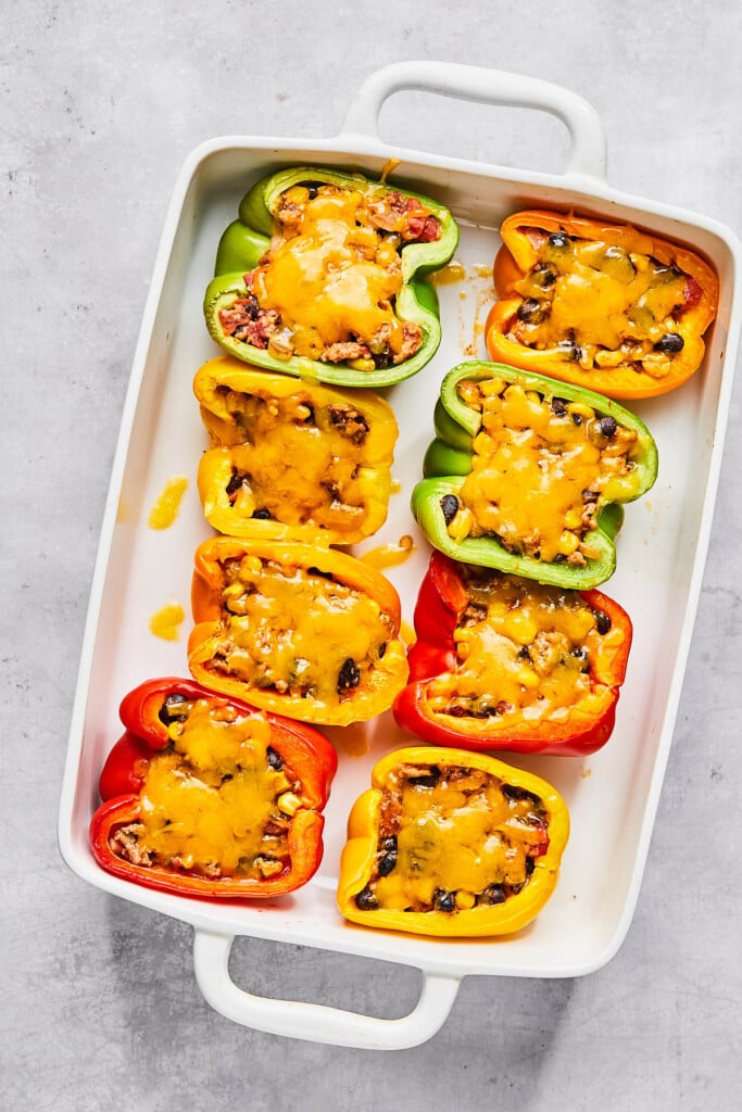 Healthy stuffed peppers with ground turkey and topped with melted cheese in a large casserole dish.