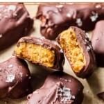 Homemade butterfinger candy bars on a piece of parchment paper. One of the bars is broken in half so you can see the inside of the bar.