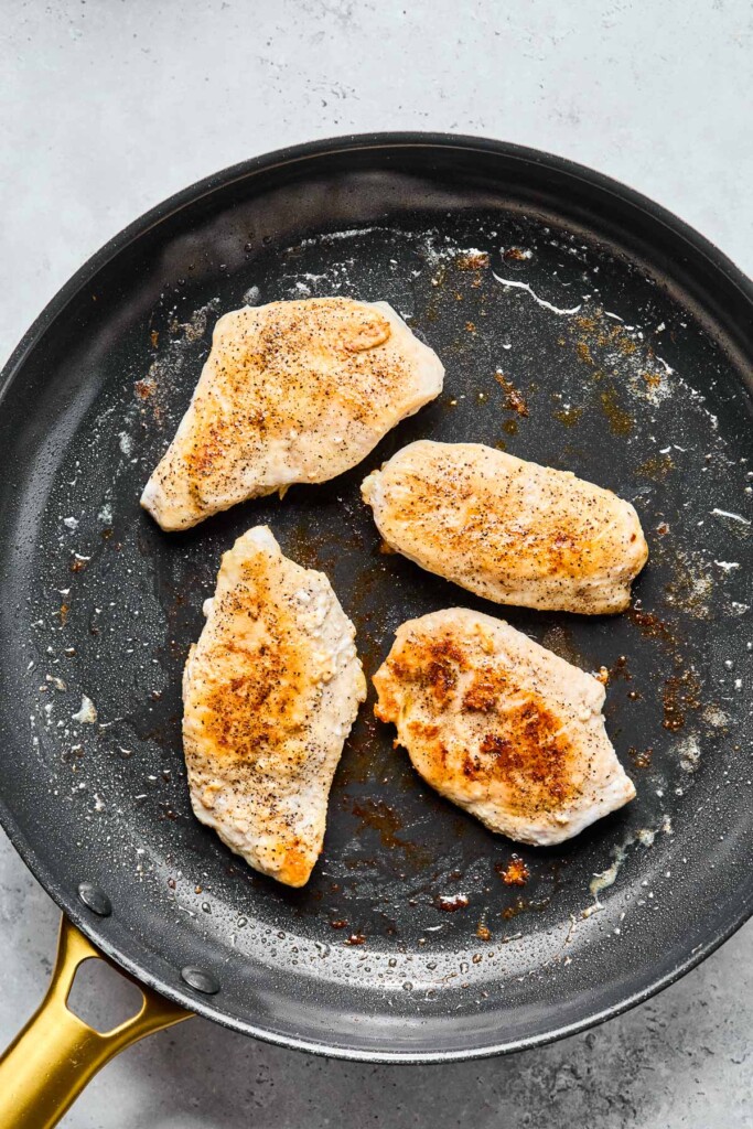 Overhead shot of a skillet with 4 cooked chicken breasts in it.