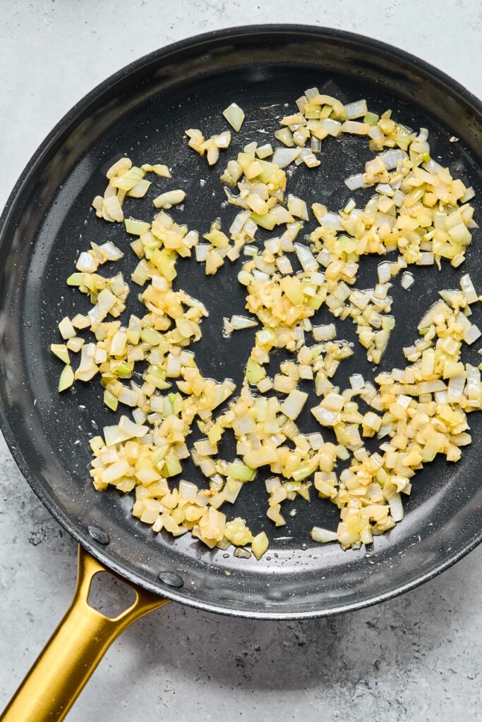 Overhead shot of a skillet with sautéed onions and garlic in it.