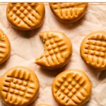 Overhead shot of no bake peanut butter cookies spread out on a piece of parchment paper. One of them has a bite taken out of it.