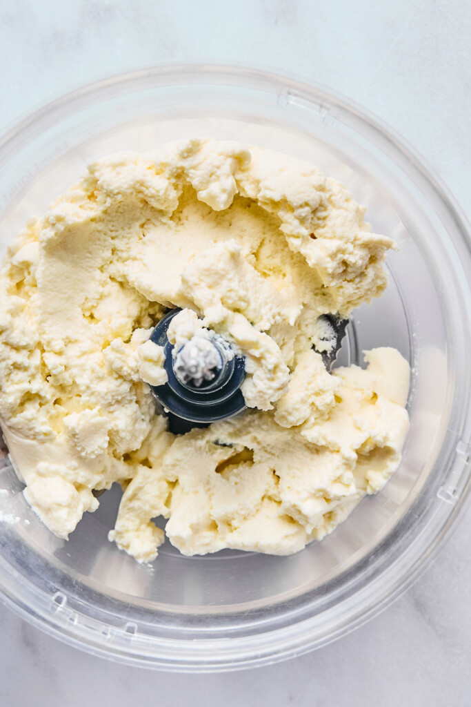 Overhead shot of ricotta cheese in the bowl of a food processor.