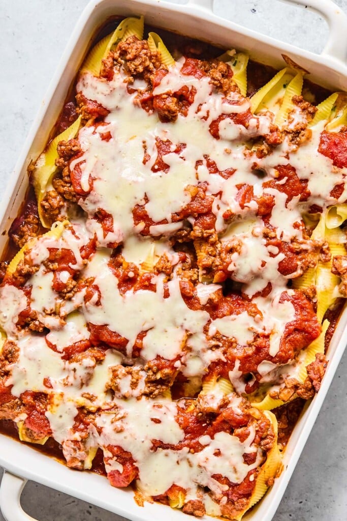 A pan of stuffed shells with meat sauce topped with melted cheese.