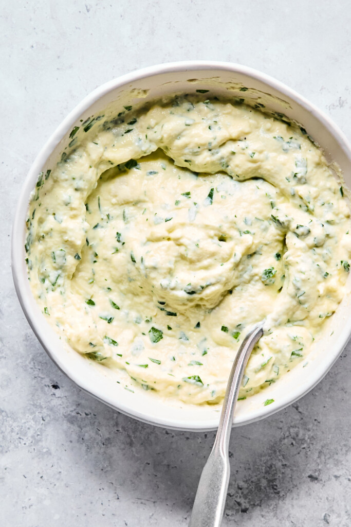 Overhead shot of a bowl with a mixture of ricotta cheese and fresh herbs.