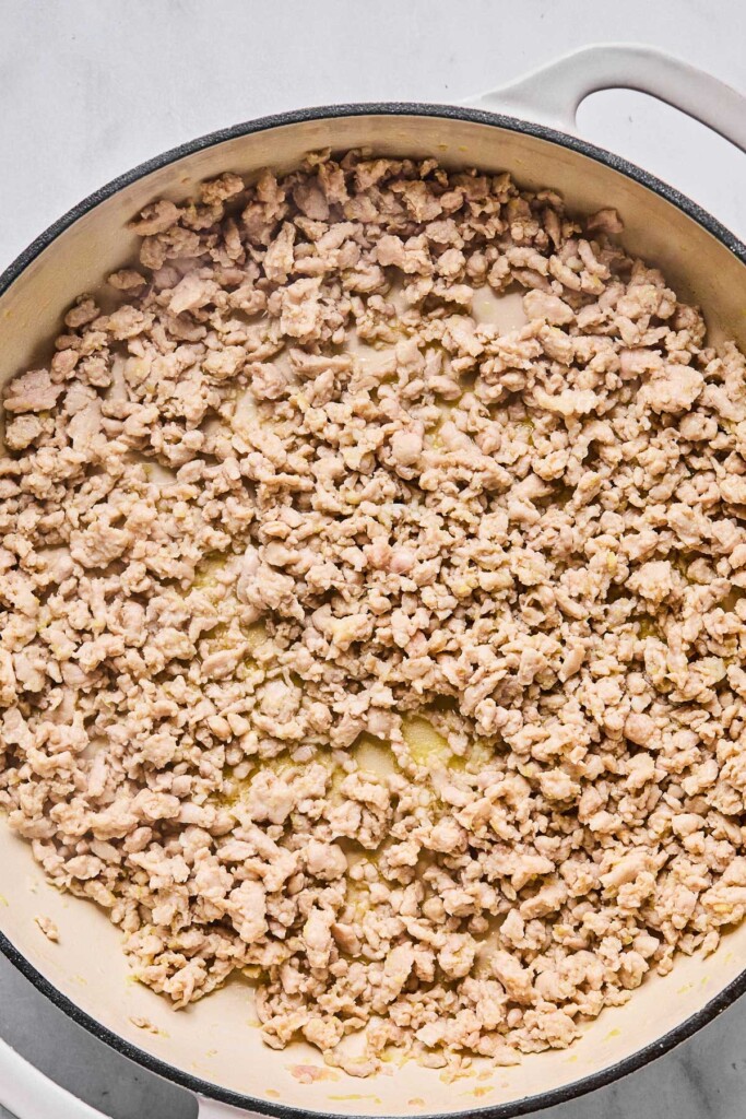 Overhead shot of a large white enameled pan filled with sautéed ground chicken.