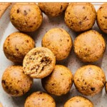 A plate of peanut butter protein balls. One of the balls is on top of the rest and it has a bite taken out of it.