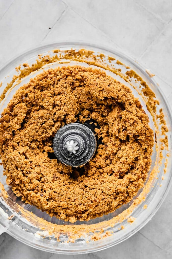 Food processor bowl filled with a slightly crumbly yet wet dough.