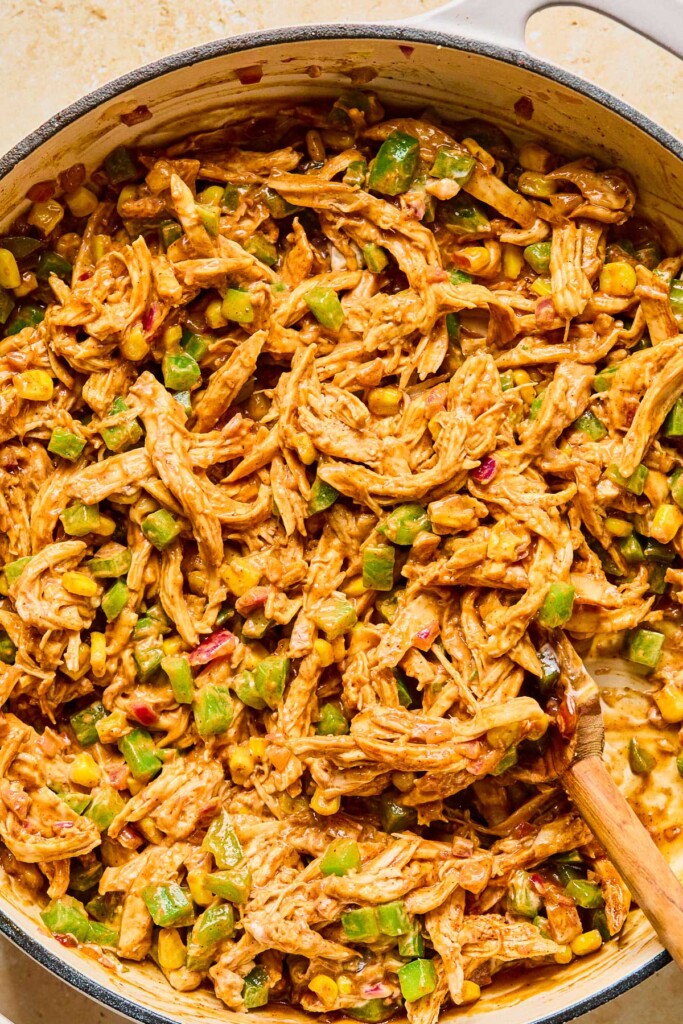 Large enameled pan filled with a mixture of shredded chicken and veggies in a creamy brownish sauce.