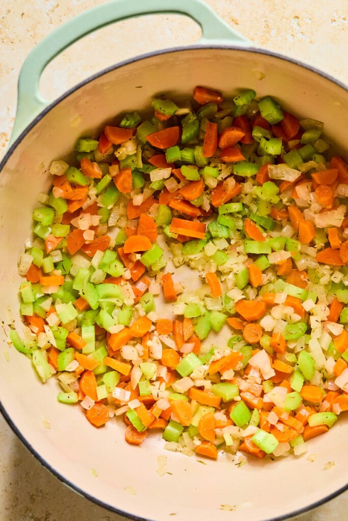 Large dutch oven filled with sautéed diced onions, carrots, and celery.