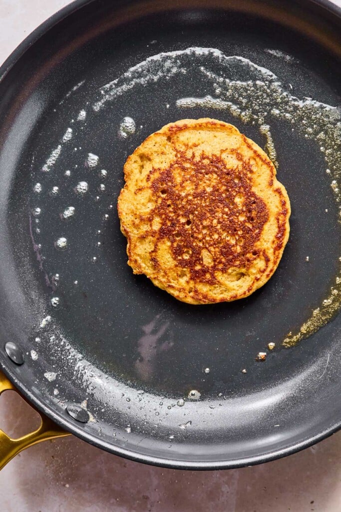 Large greased skillet with a greek yogurt oatmeal pancake cooking on it.