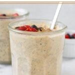 Two jars of overnight oats with protein powder, with one being behind the other. They are topped with berries and a spoon is in the jar in the front. In front of the jar is a teaspoon of cinnamon and off to the back is a dish of berries.